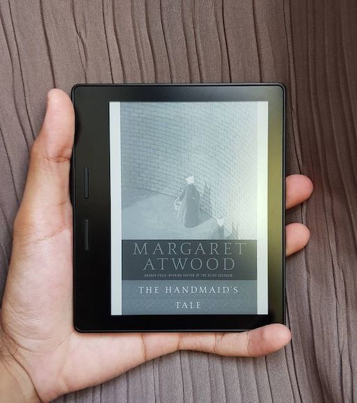A picture of a Kindle with the book cover of 'The Handmaid's Tale' on display.