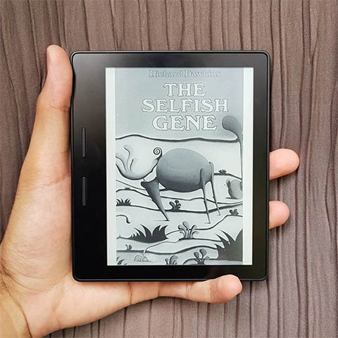 A picture of a Kindle with the cover of The Selfish Gene book on display.