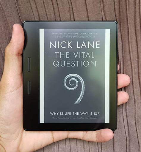 A picture of a Kindle with the cover of The Vital Question book on display.